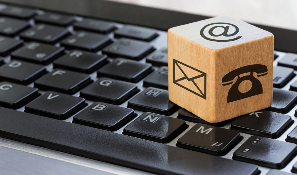 Drewniana kostka z symbolem koperty leżąca na klawiaturze komputera